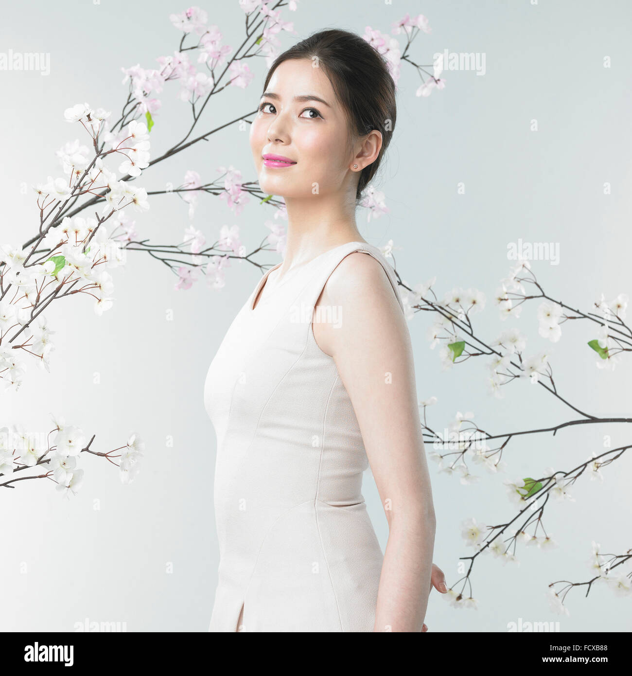 Donna sorridente e guardando in alto con lo sfondo del fiore di ciliegio filiali Foto Stock