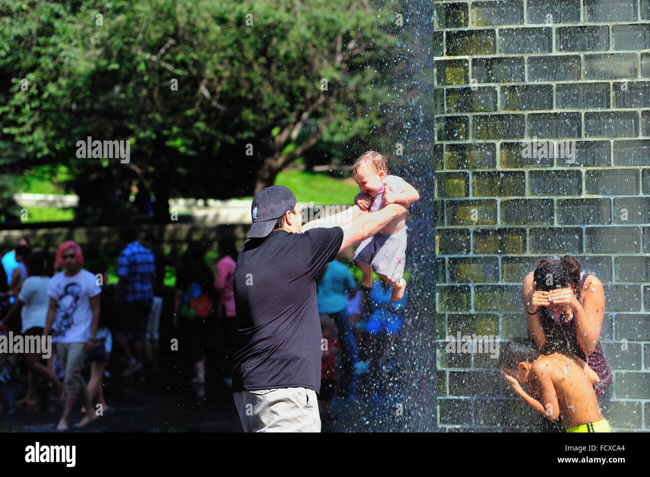 Padre "battezza' figlia in Crown Foundation in una calda giornata estiva in Millennium Park di Chicago, Illinois, Stati Uniti d'America. Foto Stock