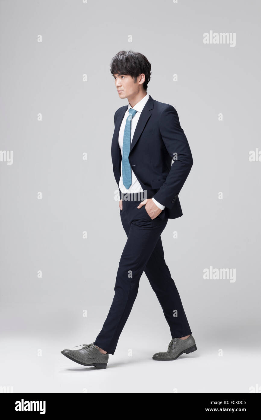 Uomo in abito nero e cravatta blu a piedi con le mani in tasca dei suoi pantaloni e guardando in alto Foto Stock