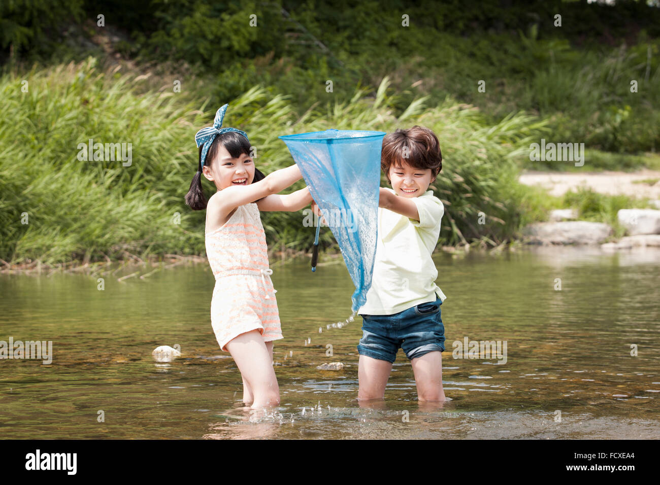 Due bambini divertirsi nella valle poco profonda con una rete da pesca Foto Stock