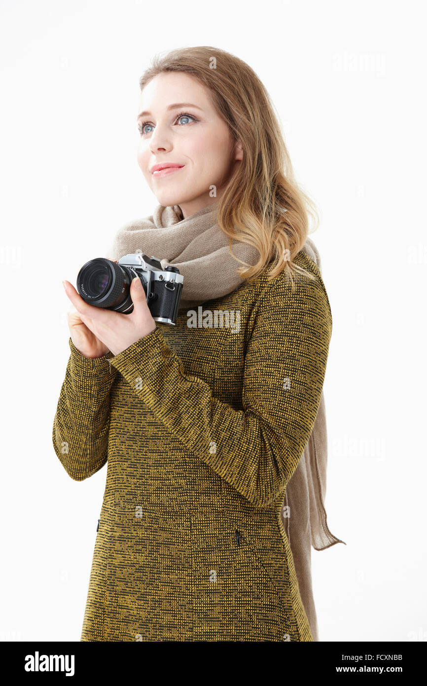 Ritratto di giovane donna sorridente indossando una sciarpa tenendo una fotocamera cercando Foto Stock