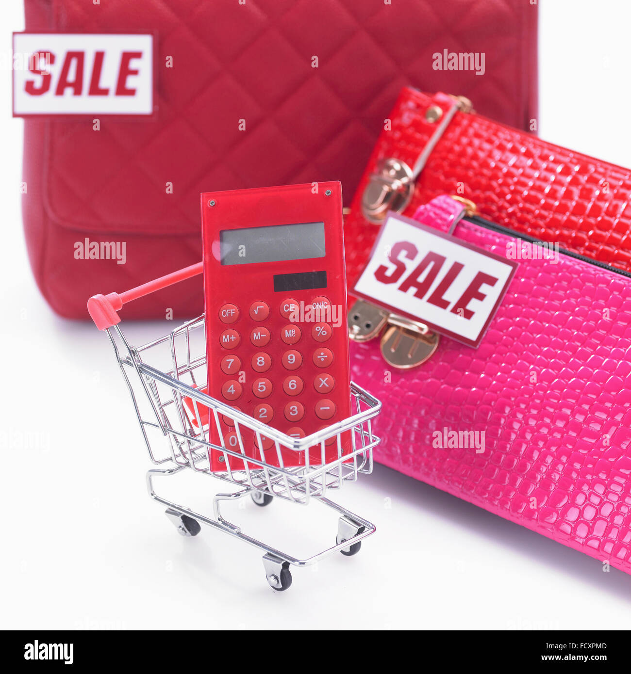 Calcolatrice in un carrello della spesa con i sacchetti con segno di vendita Foto Stock