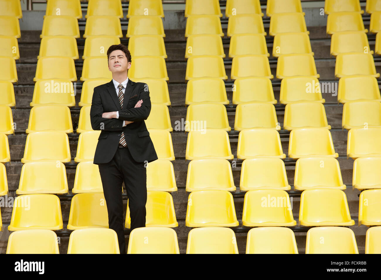 Imprenditore in piedi i bracci piegatori a stadium sedi Foto Stock