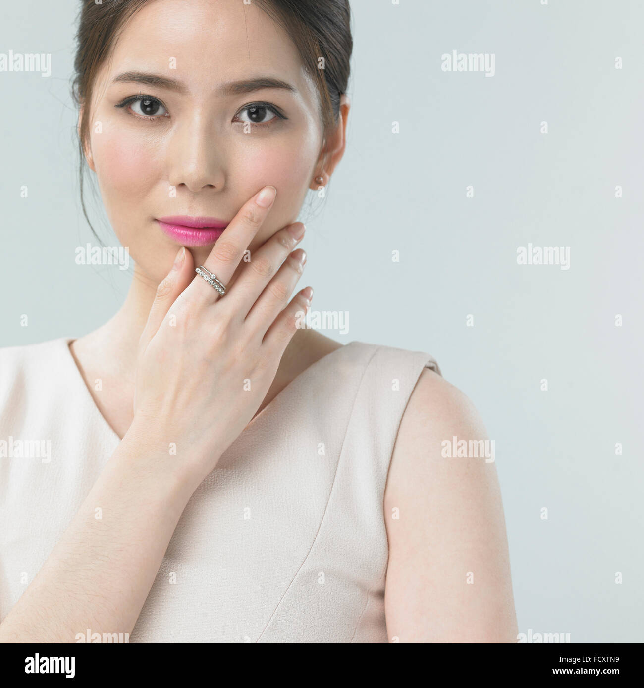Ritratto di giovane donna con labbra rosa toccando il suo volto fissando sulla parte anteriore Foto Stock