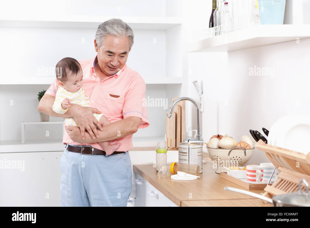 Il vecchio uomo di prendersi cura di un bambino in cucina Foto Stock