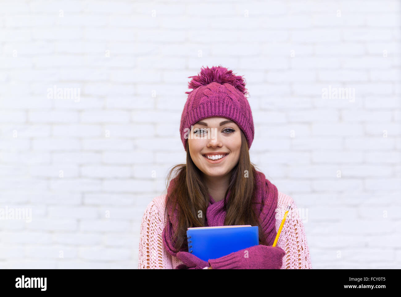 Attraente studente Sorriso ragazza adolescente in rosa Hat Holding matita cartella Foto Stock