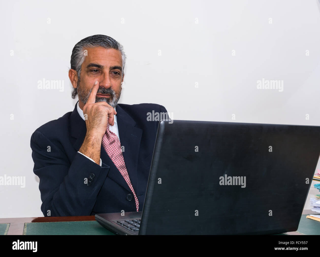 Imprenditore in un vestito e cravatta, nel suo studio. Alla scrivania, utilizzando il PC. Foto Stock