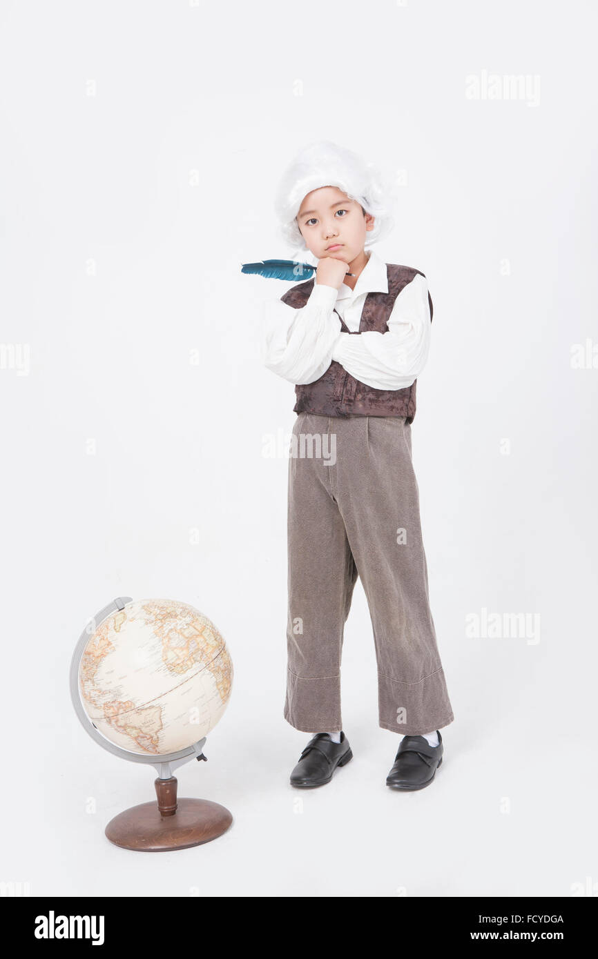 Ragazzo in classico stile studioso tenendo una piuma penna e in piedi dietro un globo con il gesto di pensare Foto Stock