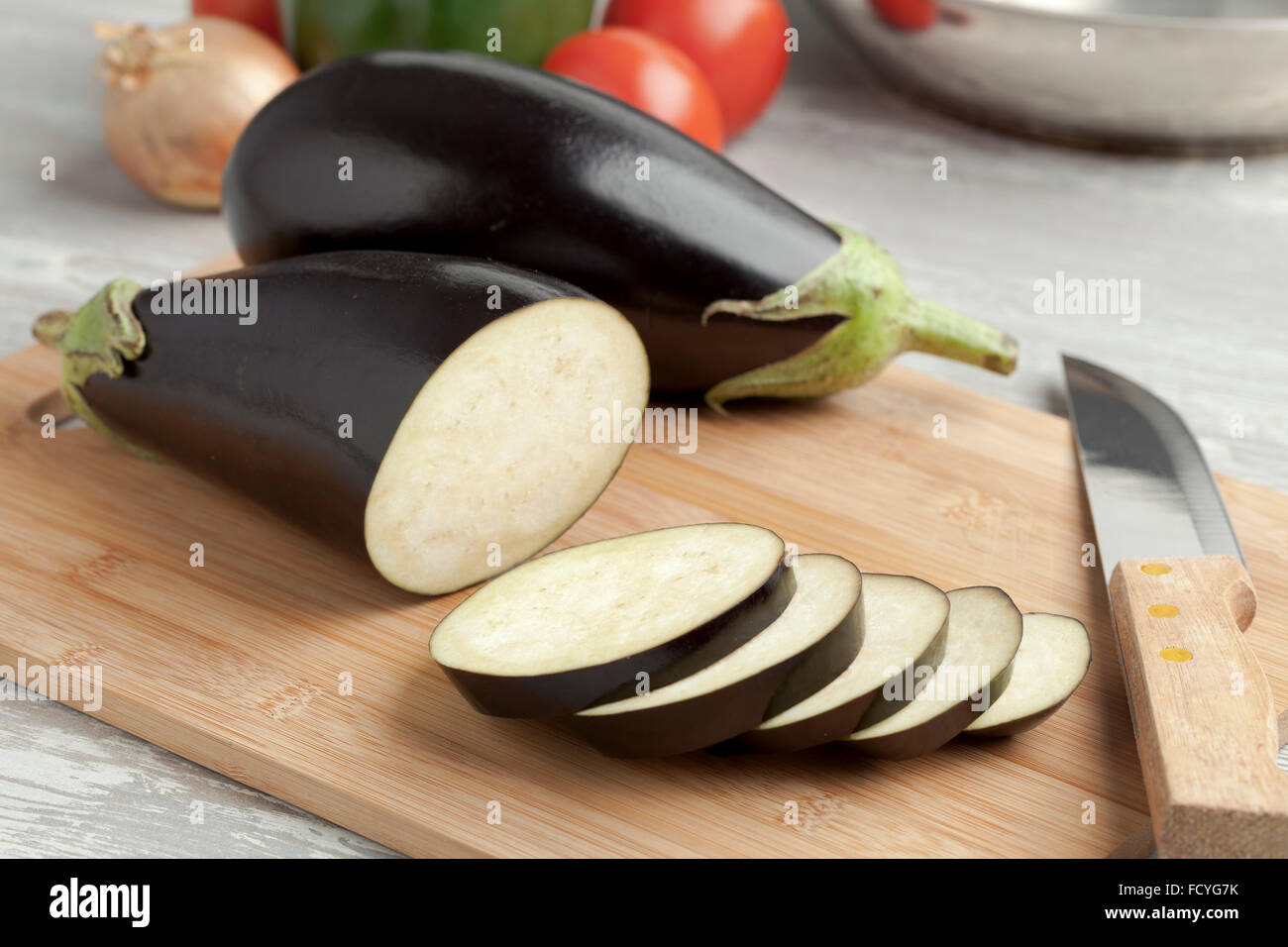 Intero fresco melanzane viola e le fette su un tagliere Foto Stock