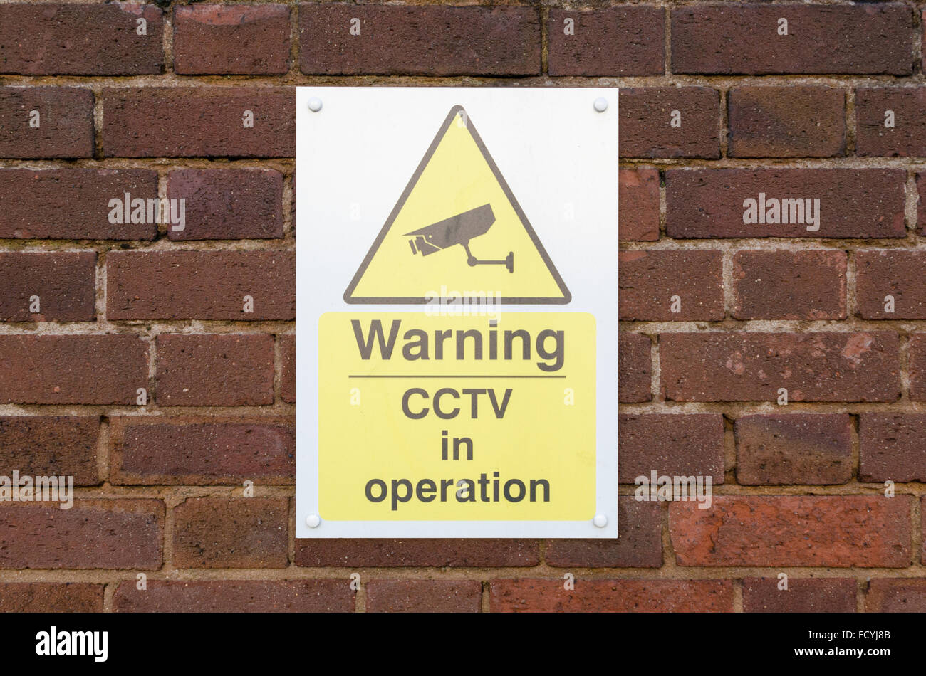 Segno di avvertimento CCTV in operazione su un muro di mattoni Foto Stock