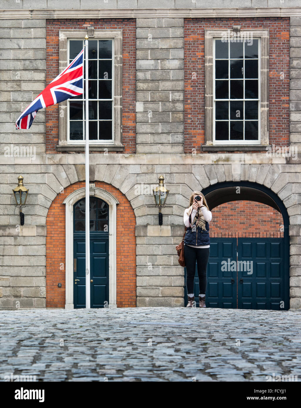 Turistica prendendo le foto nel cortile del Castello di Dublino in Irlanda con la britannica Union Jack battenti in background. Foto Stock