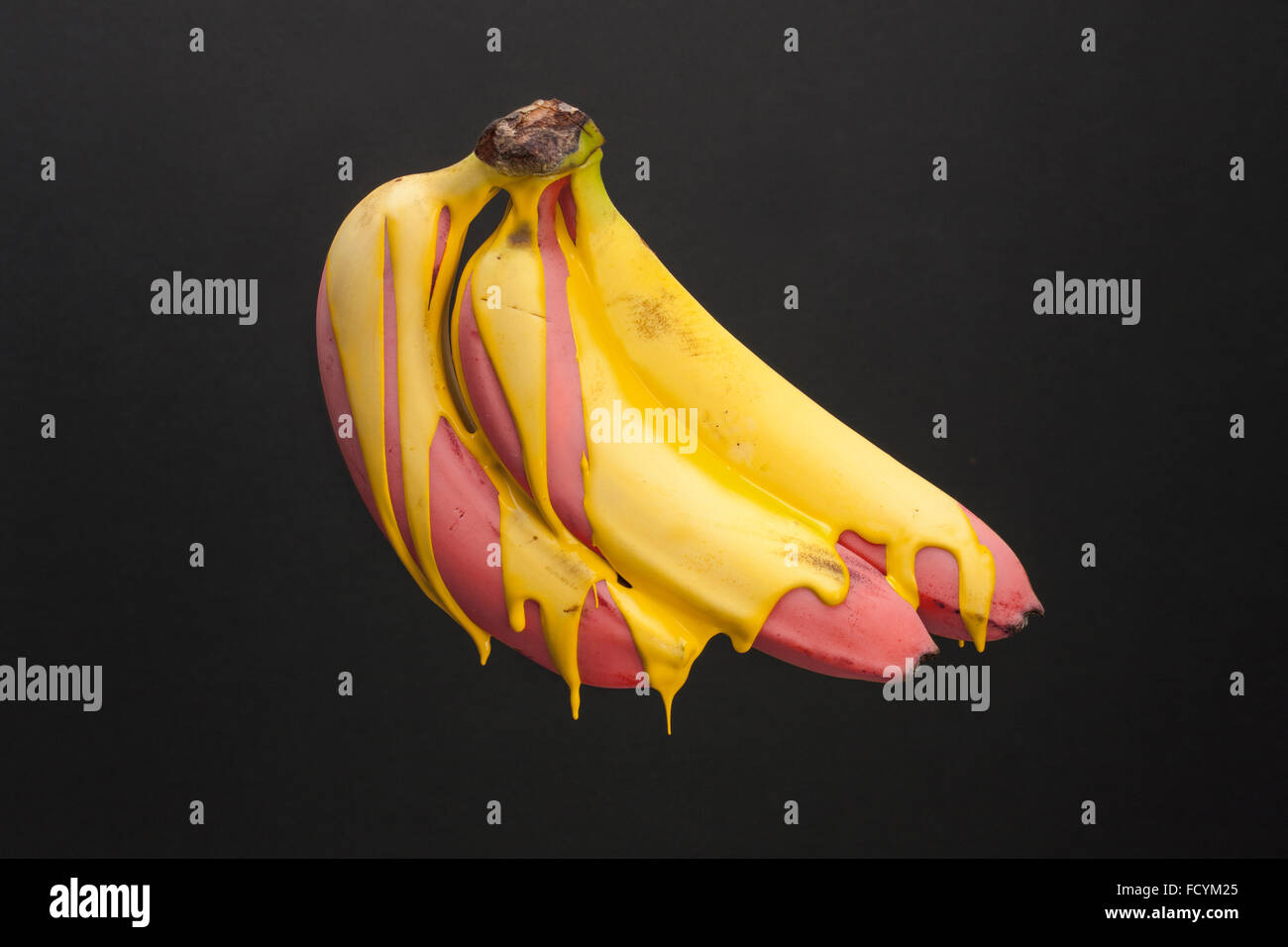 Banane Rosso con vernice gialla gocciolamento verso il basso Foto Stock