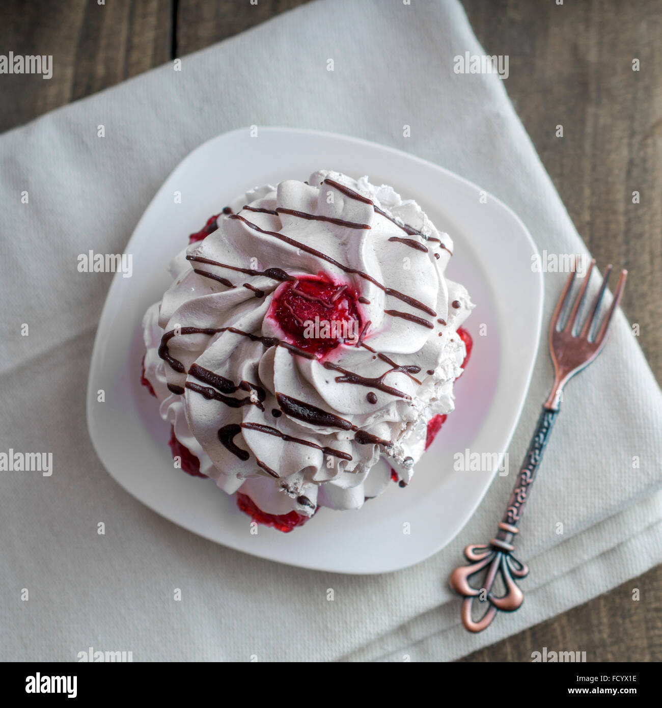 Singola tortina di vaniglia decorata con cioccolato sullo sfondo di legno Foto Stock