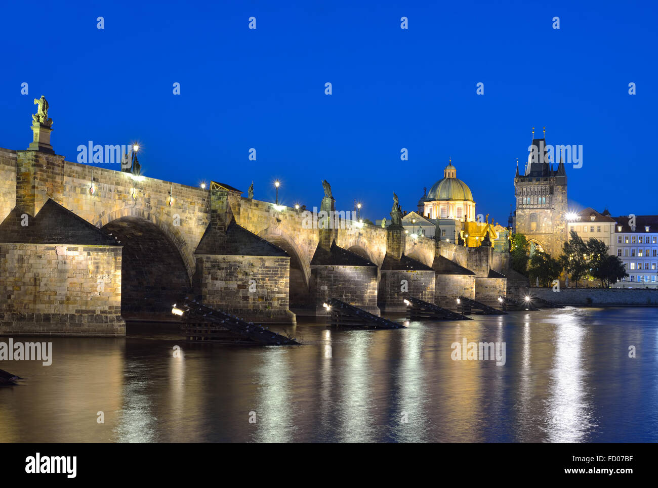 Il fiume Moldava, il Ponte Carlo e la Torre del Ponte della Città Vecchia di Praga di notte contro un cielo blu. Karluv la maggior parte. Repubblica ceca Foto Stock
