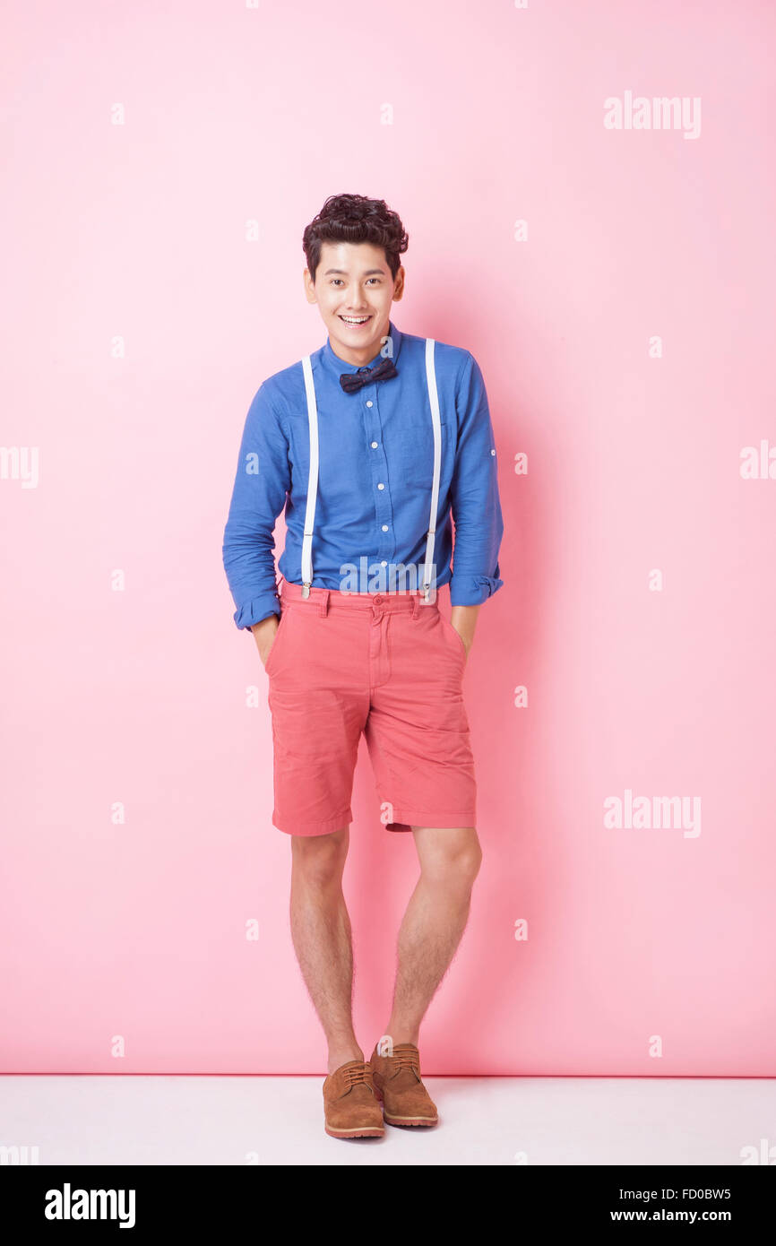 Giovane uomo adulto in stile retrò con il filtro bow tie in piedi su sfondo rosa con le mani in tasca Foto Stock