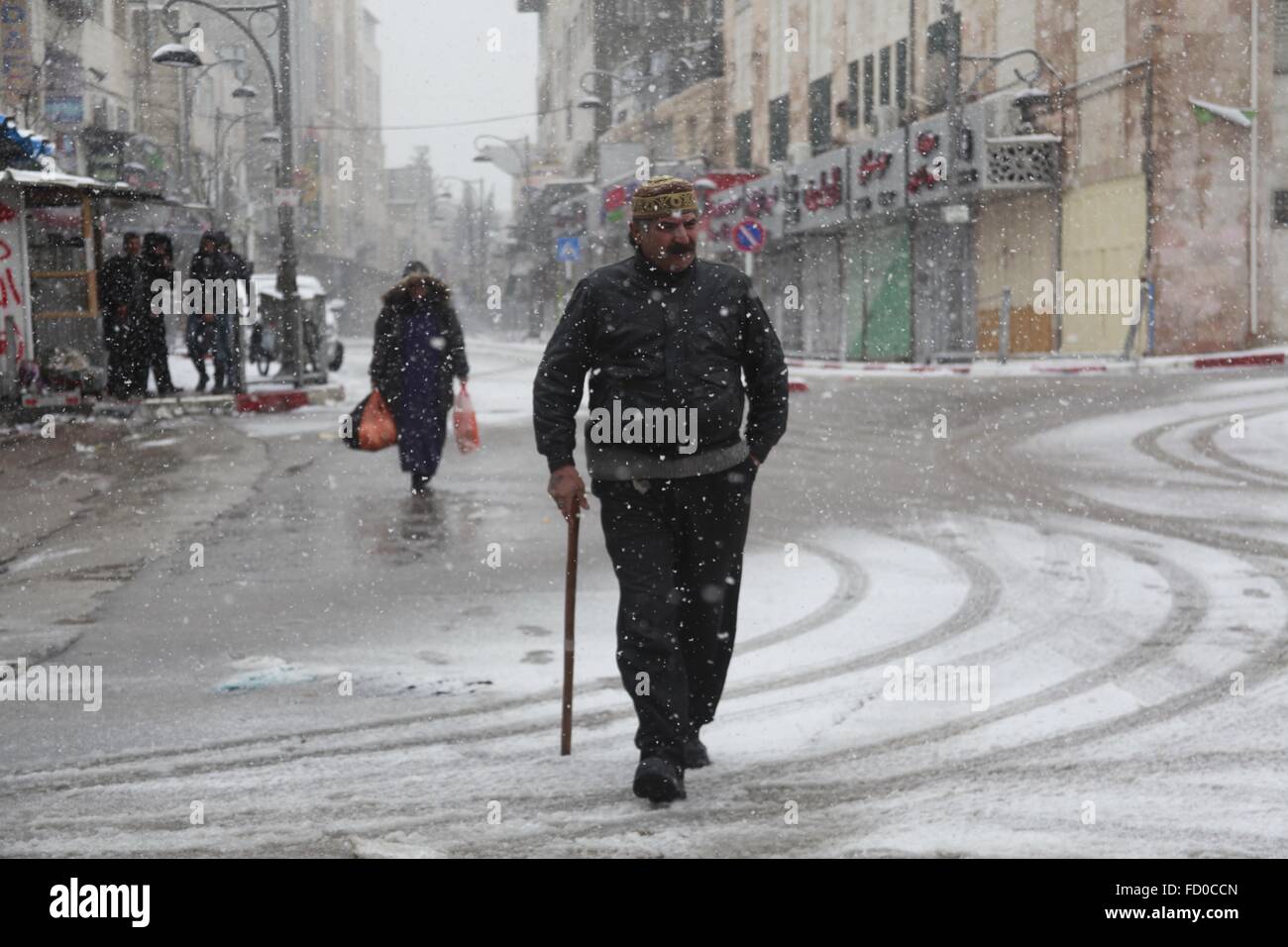 Hebron. 26 gen, 2016. Un palestinese uomo cammina per la strada durante una tempesta di neve in Cisgiordania città di Hebron, a gennaio 26, 2016. Tempesta condizioni meteo in tutta la regione hanno continuato come forti tempeste ha colpito la zona con neve e piogge torrenziali. © Mamoun Wazwaz/Xinhua/Alamy Live News Foto Stock