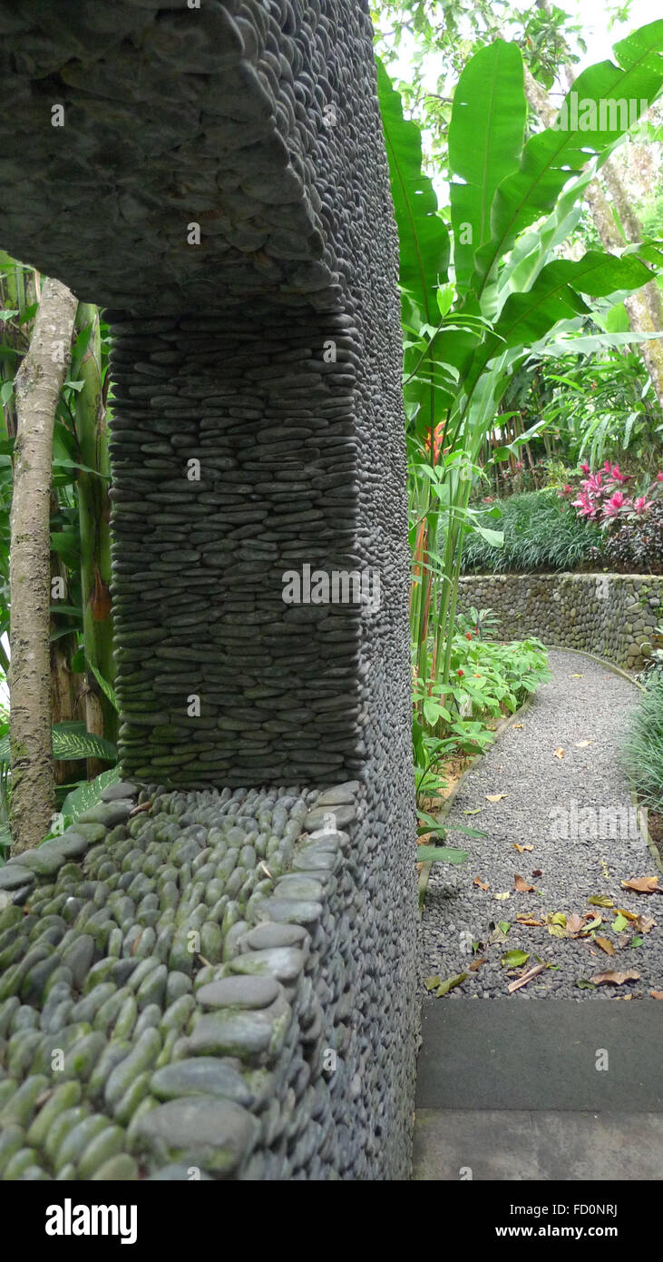 Impilati muro di pietra con apertura e percorso tropicale Foto Stock