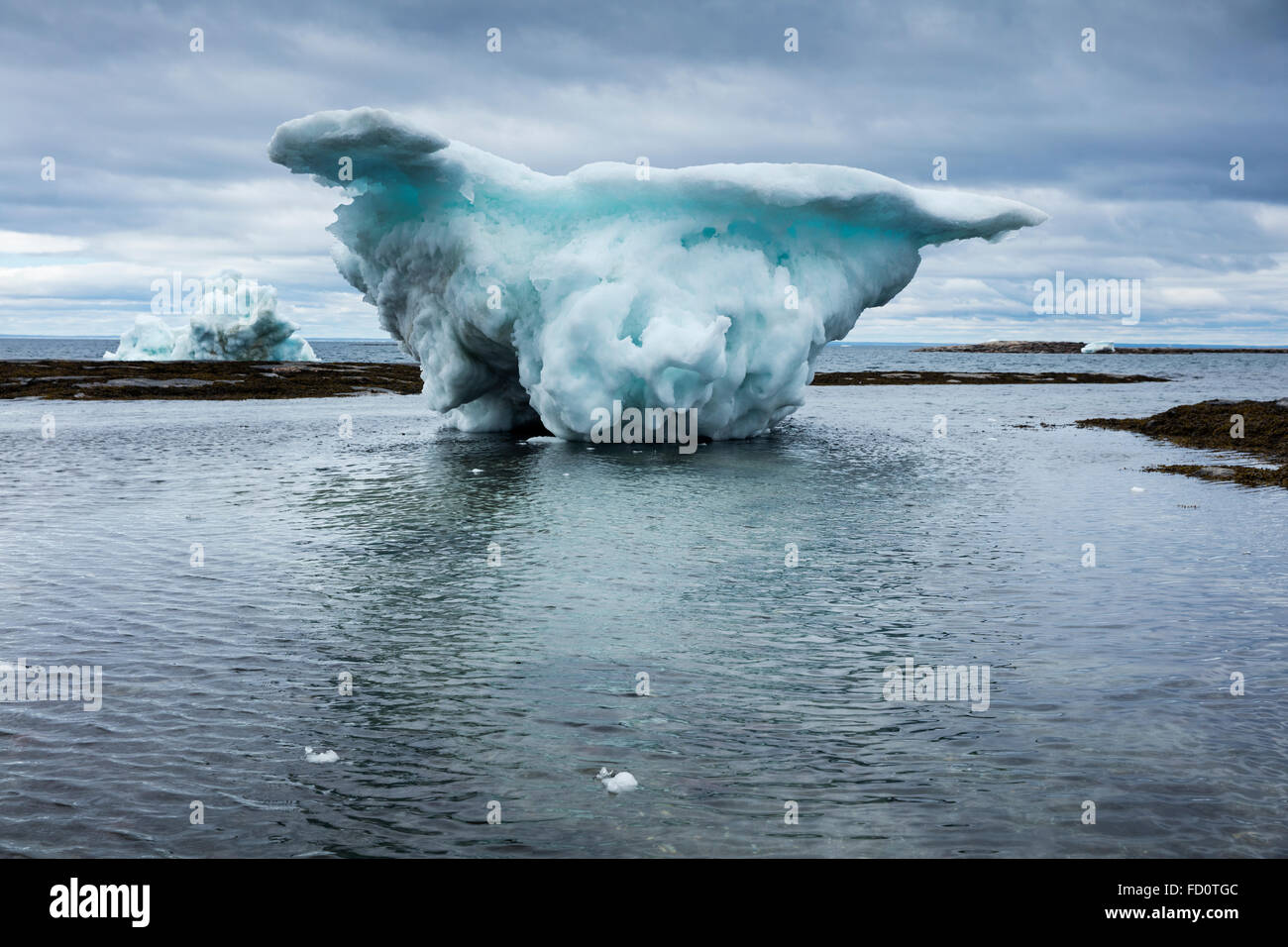 Canada, Nunavut Territorio, Repulse Bay, Iceberg collegato a massa a bassa marea nelle isole del porto sul pomeriggio estivo Foto Stock
