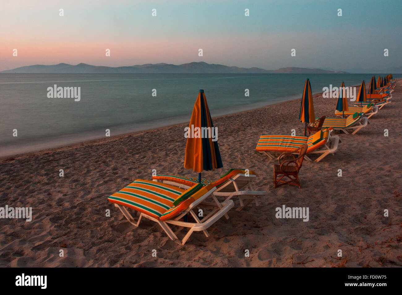 Sdraio sulla spiaggia al tramonto presi su Kos guardando verso Pserimos Foto Stock