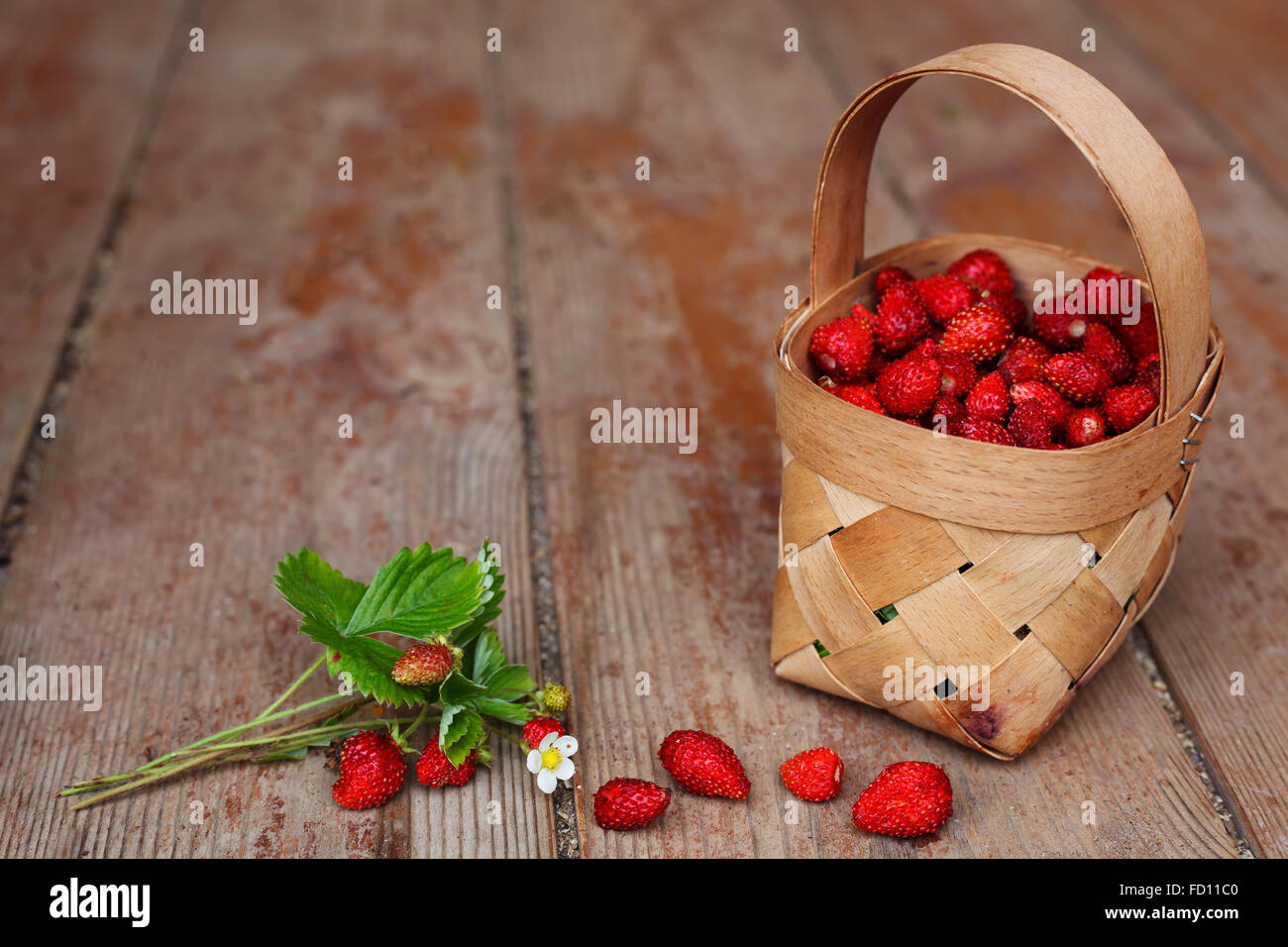 Cestello con bacche mature (fragole) sullo sfondo del pianale in legno Foto Stock