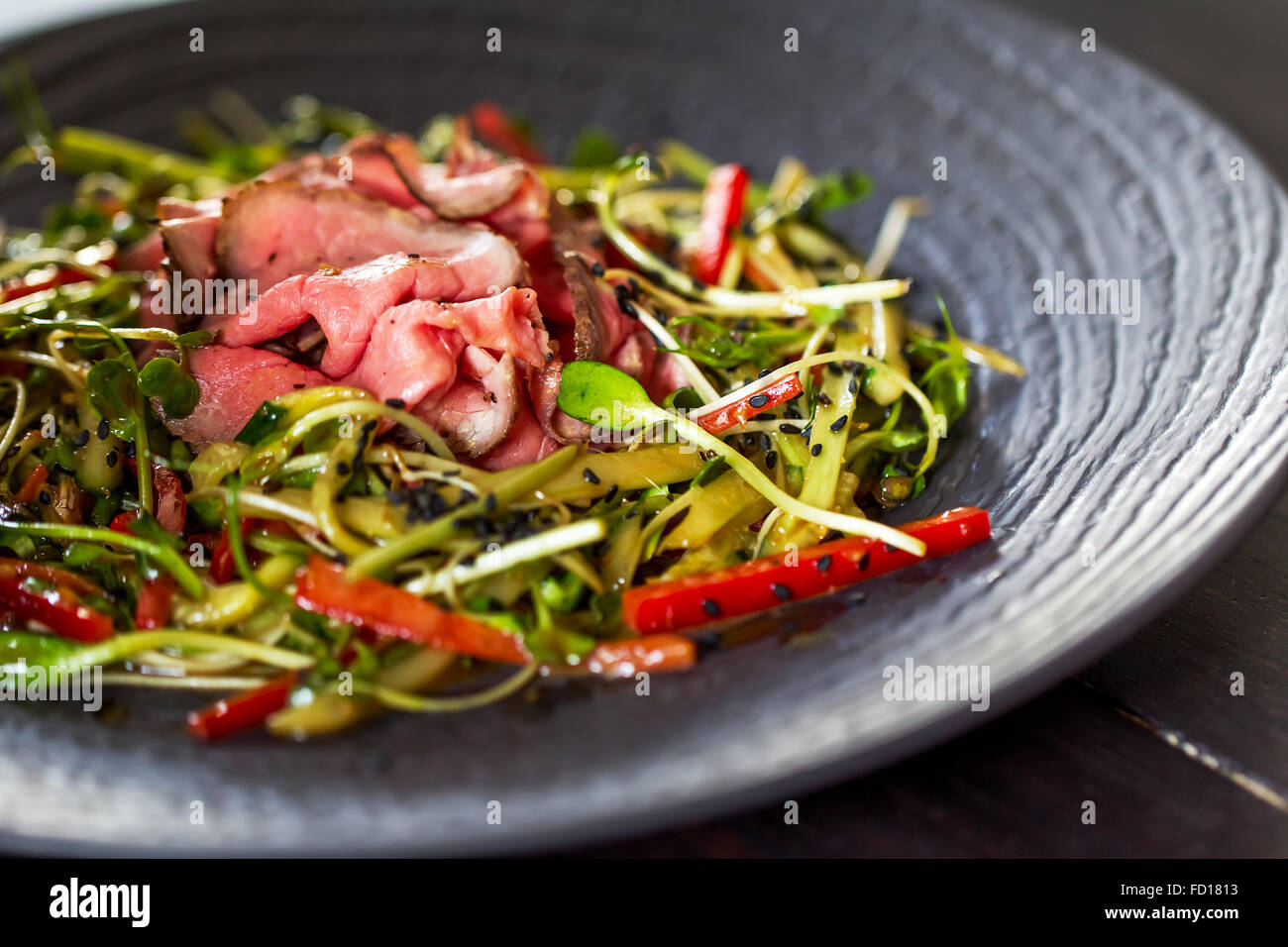 Autentica insalata con pancetta dolce peperone rosso, germogli di soia, di sesamo e di olio di oliva su una piastra nera. Mattina illuminazione atmosferica, Foto Stock