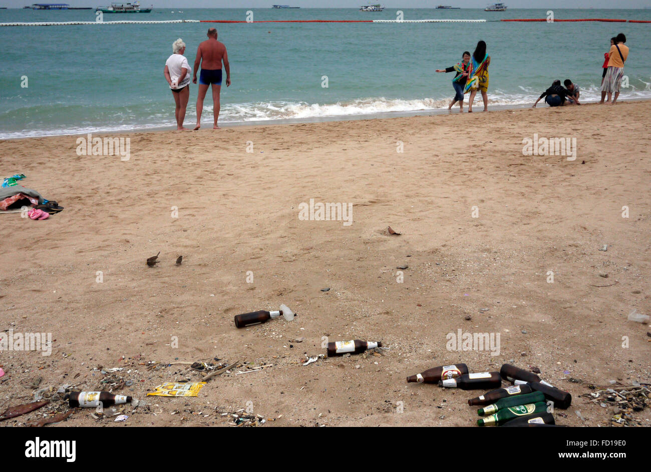 Le bottiglie da birra vuote abbandonati littering la spiaggia di Pattaya Thailandia con turisti foto di kayak in mare. Foto Stock