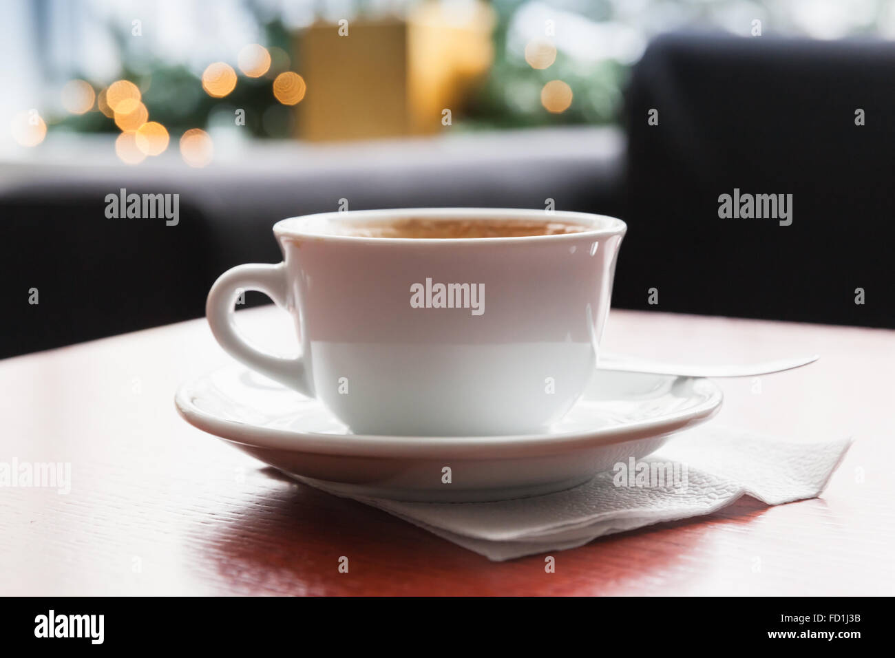 Il Cappuccino. Tazza di caffè con schiuma di latte si erge su rosso tavolo in legno nella caffetteria, closeup foto con messa a fuoco selettiva e sfocate Foto Stock