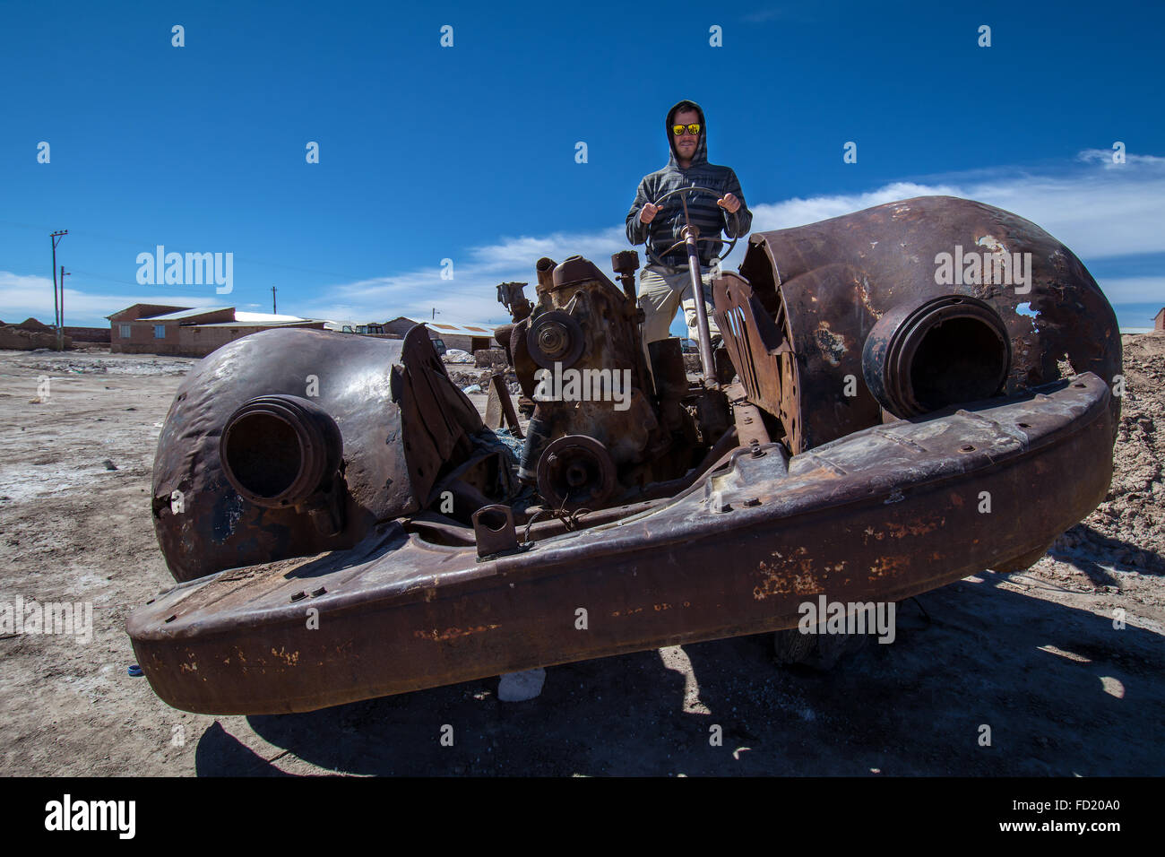 Giovane seduto in un'auto vecchia arrugginita, Cementerio de los Trenes, comune di Uyuni, Dipartimento di Potosí, Altiplano, Bolivia Foto Stock