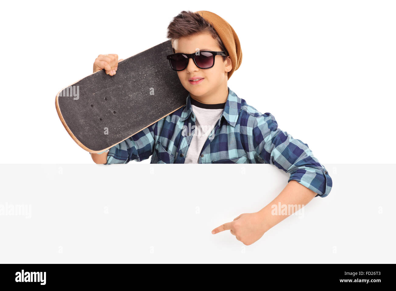 Cool kid tenendo uno skateboard e puntando su un pannello vuoto con la sua mano isolati su sfondo bianco Foto Stock