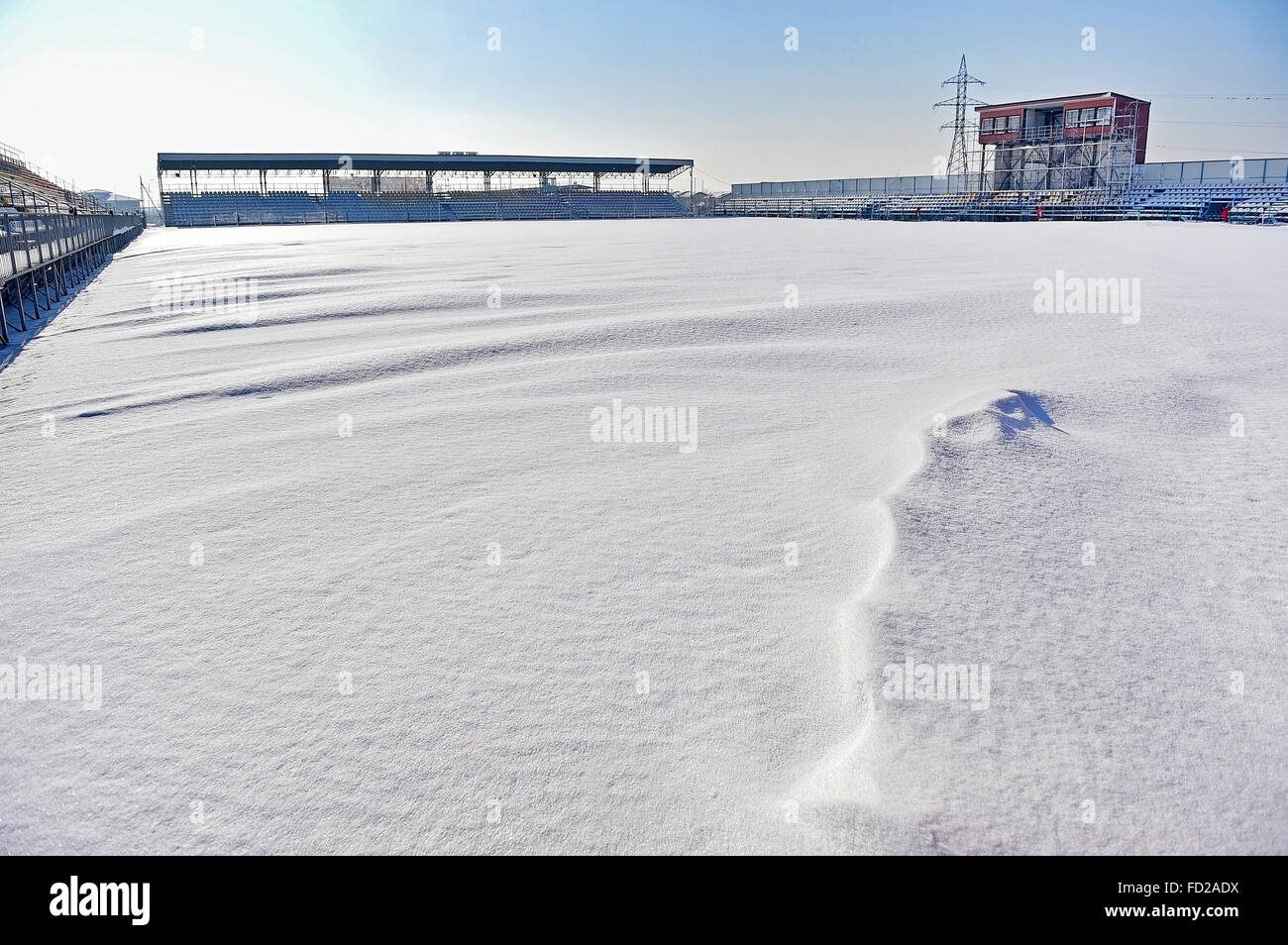 Tribune vuote e di uno stadio di calcio coperto di neve dopo una nevicata Foto Stock