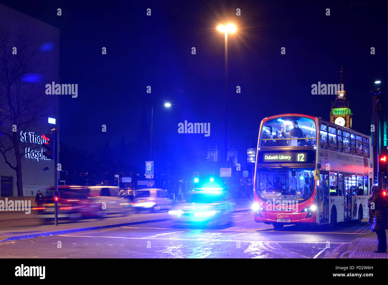 Met auto della polizia con luce blu lampeggiante luce che illuminano il cielo di notte sul Westminster Bridge con bus londinese in attesa al semaforo rosso England Regno Unito Foto Stock