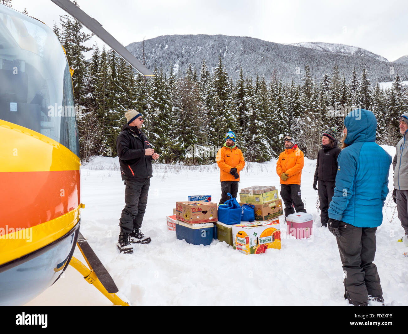 Elicottero pilota dà istruzioni di sicurezza al paese indietro gli sciatori prima del trasporto a montaggio remoto Carlyle Lodge; Canada Foto Stock