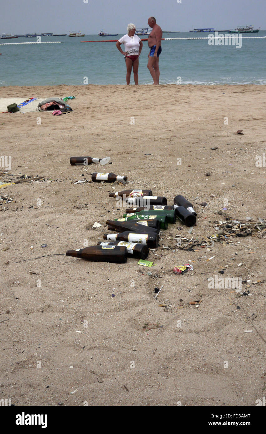 Le bottiglie da birra vuote abbandonati littering la spiaggia di Pattaya Thailandia con turisti foto di kayak in mare. Foto Stock