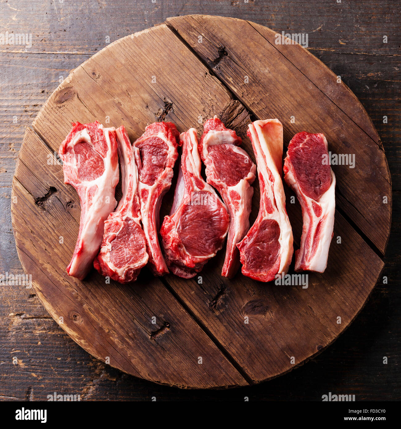 Crudo fresco costolette di agnello sul tagliere di legno su sfondo scuro Foto Stock