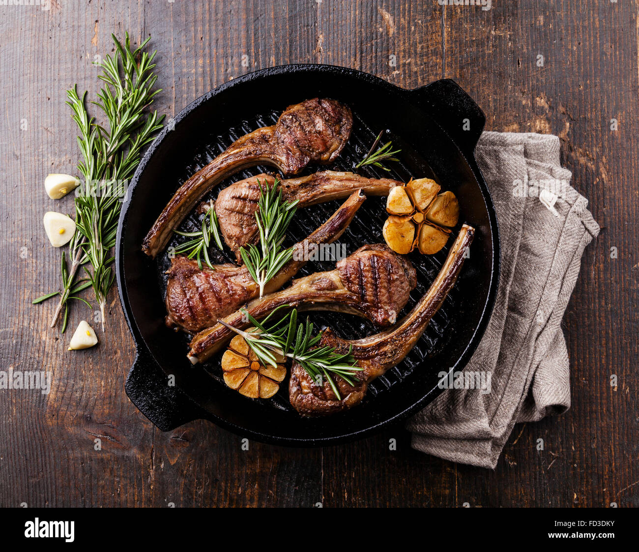 Agnello arrosto di nervature con rosmarino e aglio in padella per grigliare su scuro dello sfondo in legno Foto Stock