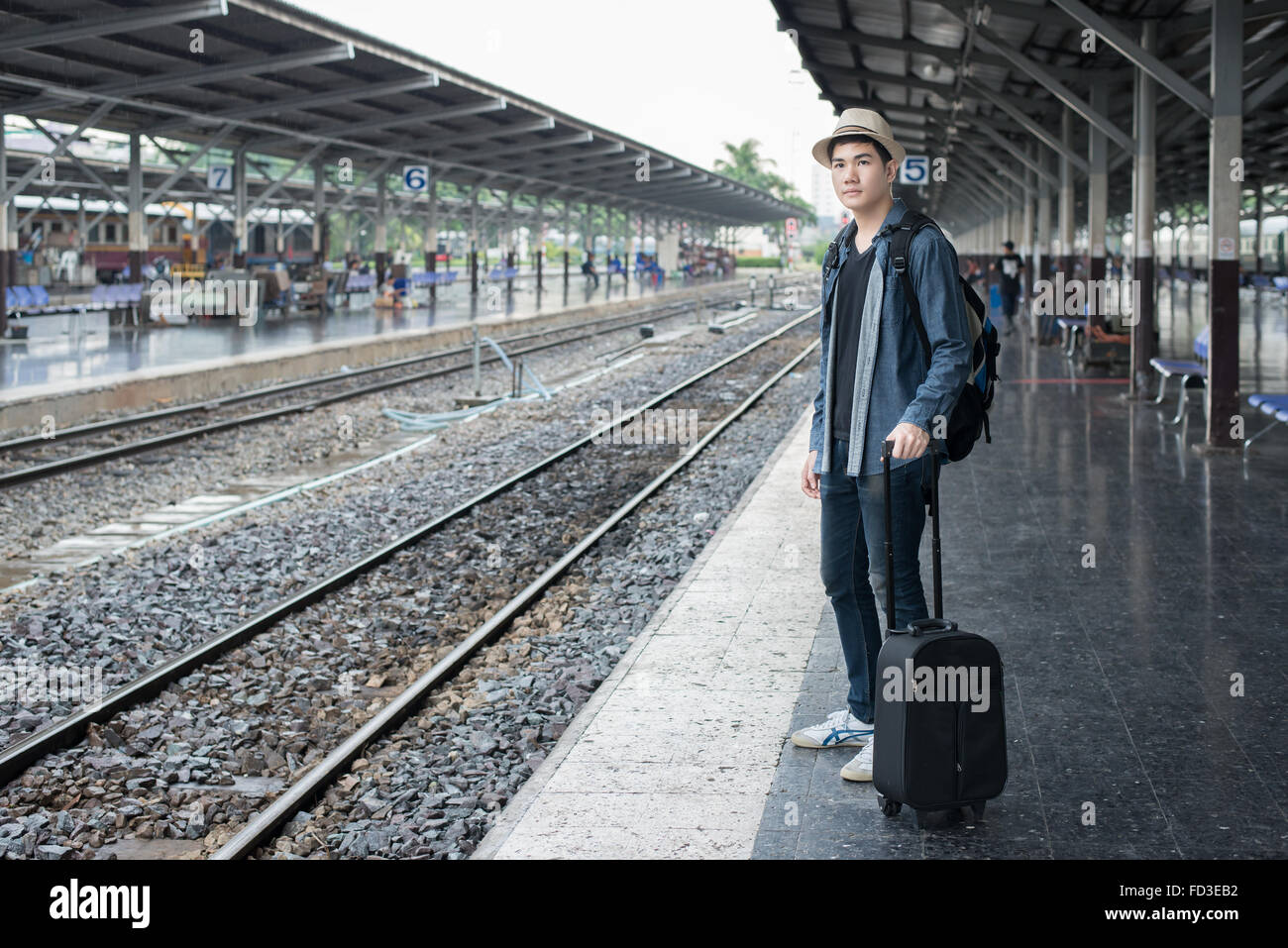 Asian Giovane aspettando il treno per il viaggio alla stazione Foto Stock