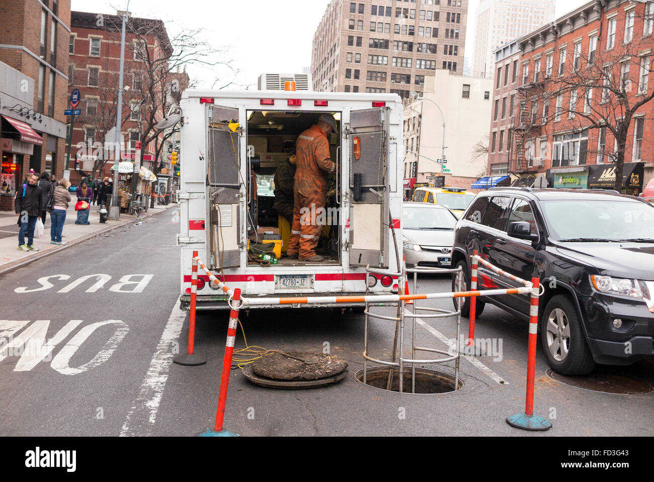 I lavoratori pubblici in piedi all'interno di un furgone oltre il tombino aperto sulla strada di New York City - Una cordata off / area protetta Foto Stock