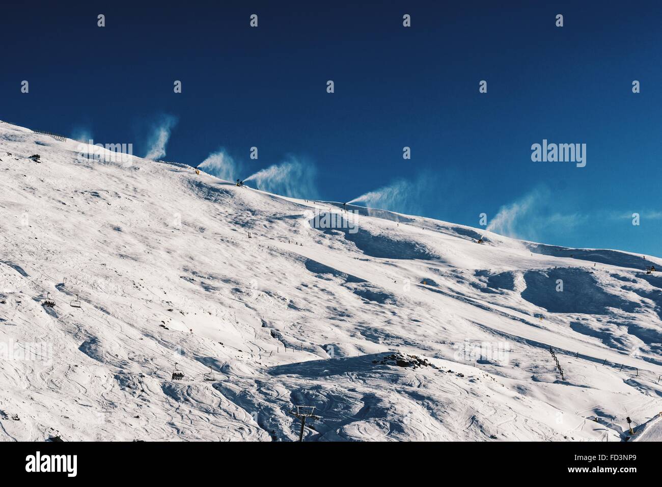 Per la produzione di neve cannoni sui Treble Cone montagna su una splendida blue bird giorno. Foto Stock