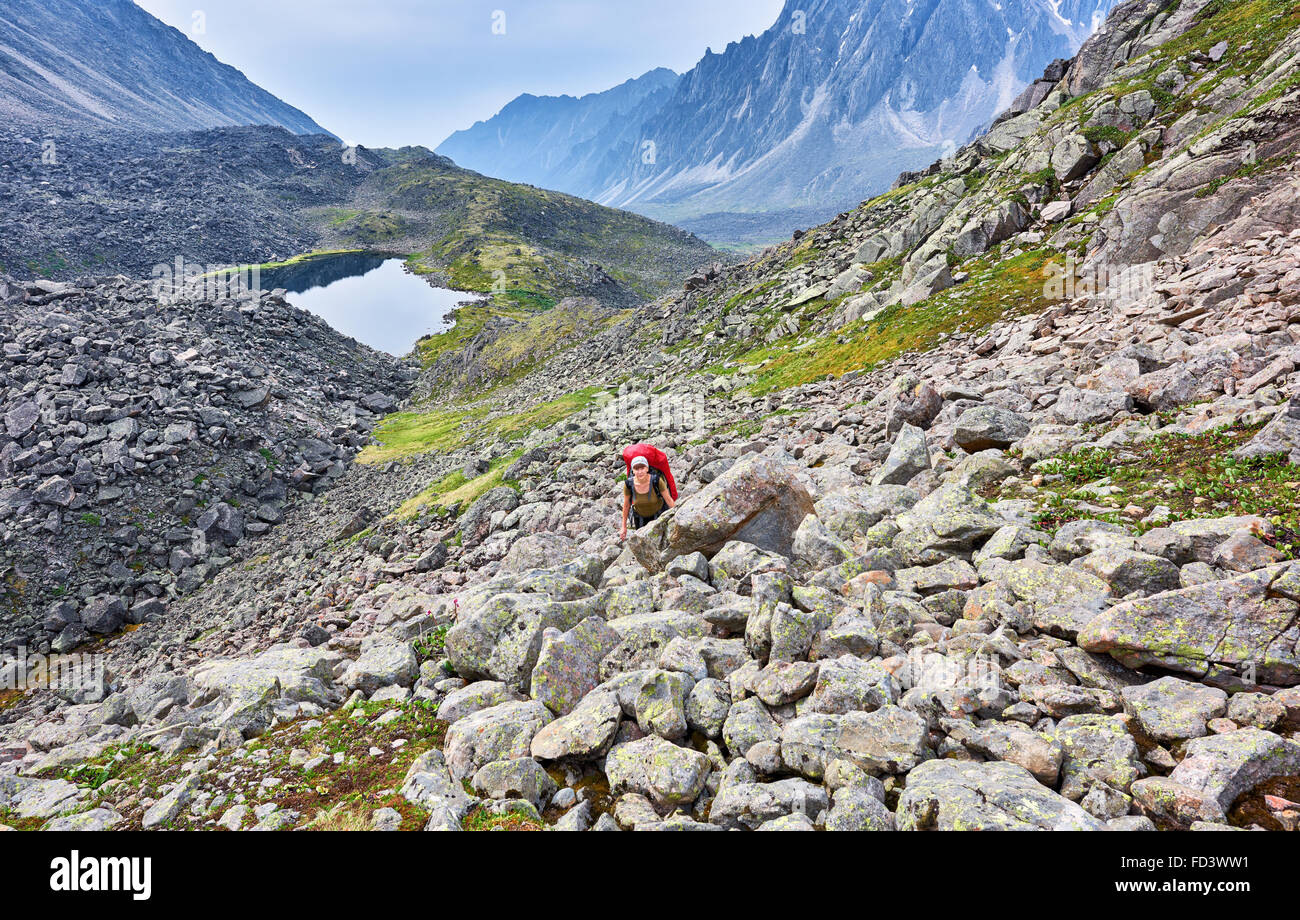 Escursionismo. La donna si arrampica la pendenza tra grandi pietre . Siberia orientale. La Russia Foto Stock