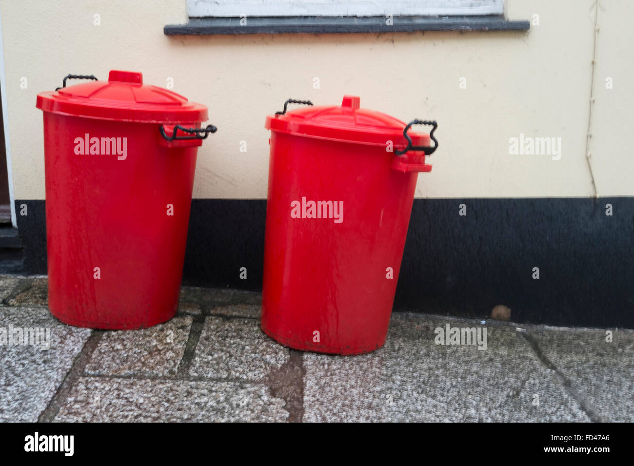 Due bidoni rossi al di fuori di una casa privata Foto Stock