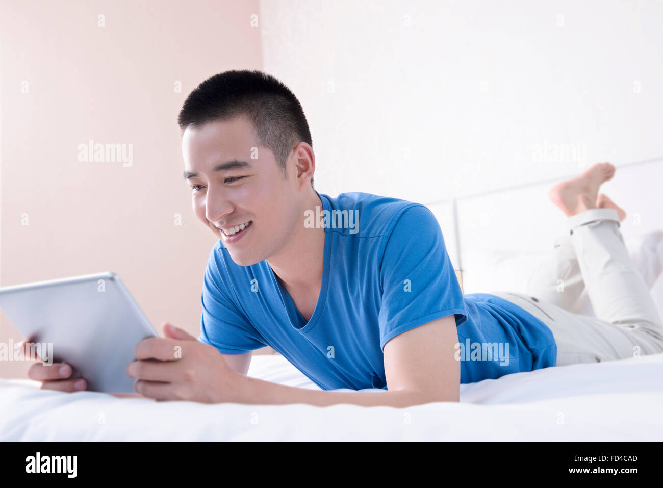 Giovane uomo con tavoletta digitale a letto Foto Stock