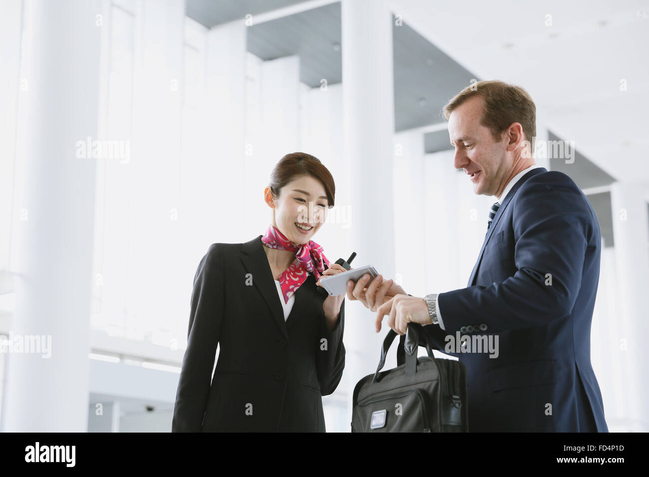 Giapponese attraente assistente di volo aiutando il cliente in aeroporto Foto Stock