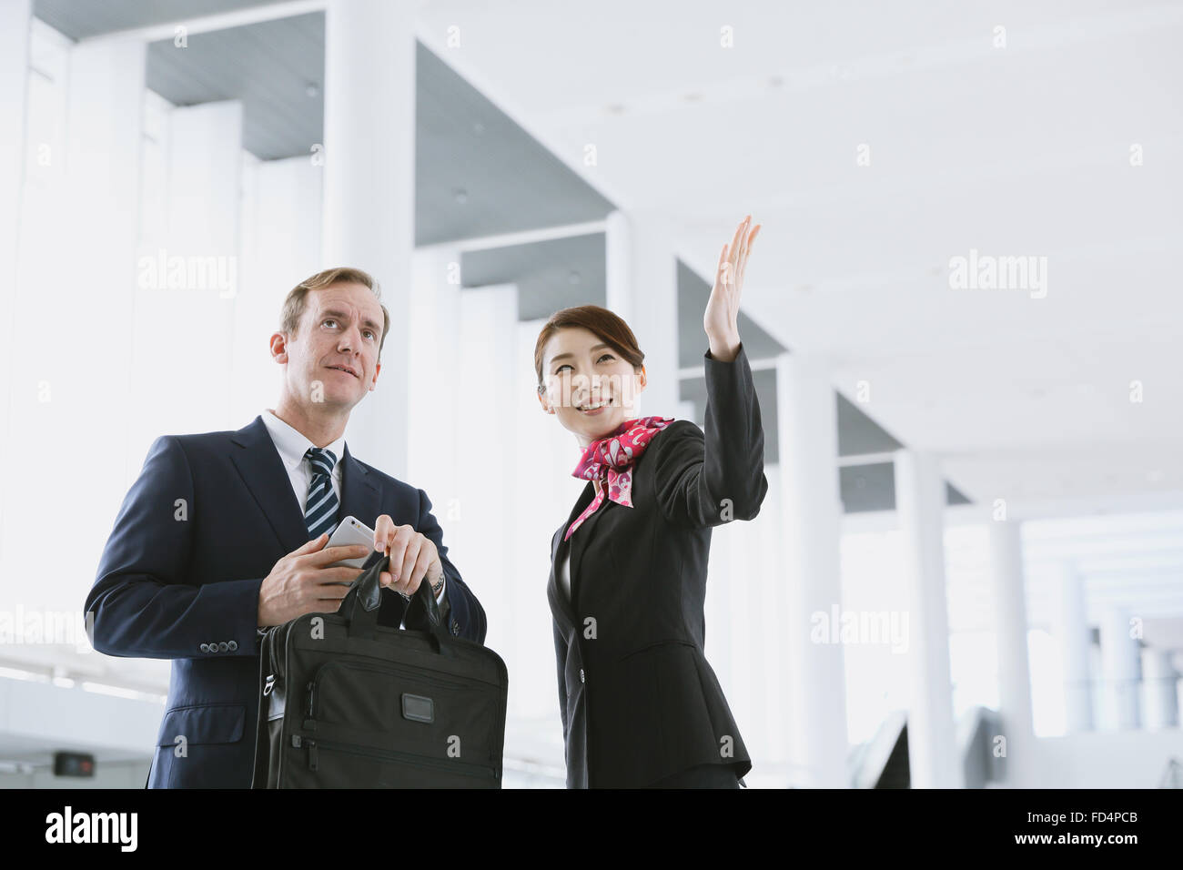 Giapponese attraente assistente di volo aiutando il cliente in aeroporto Foto Stock