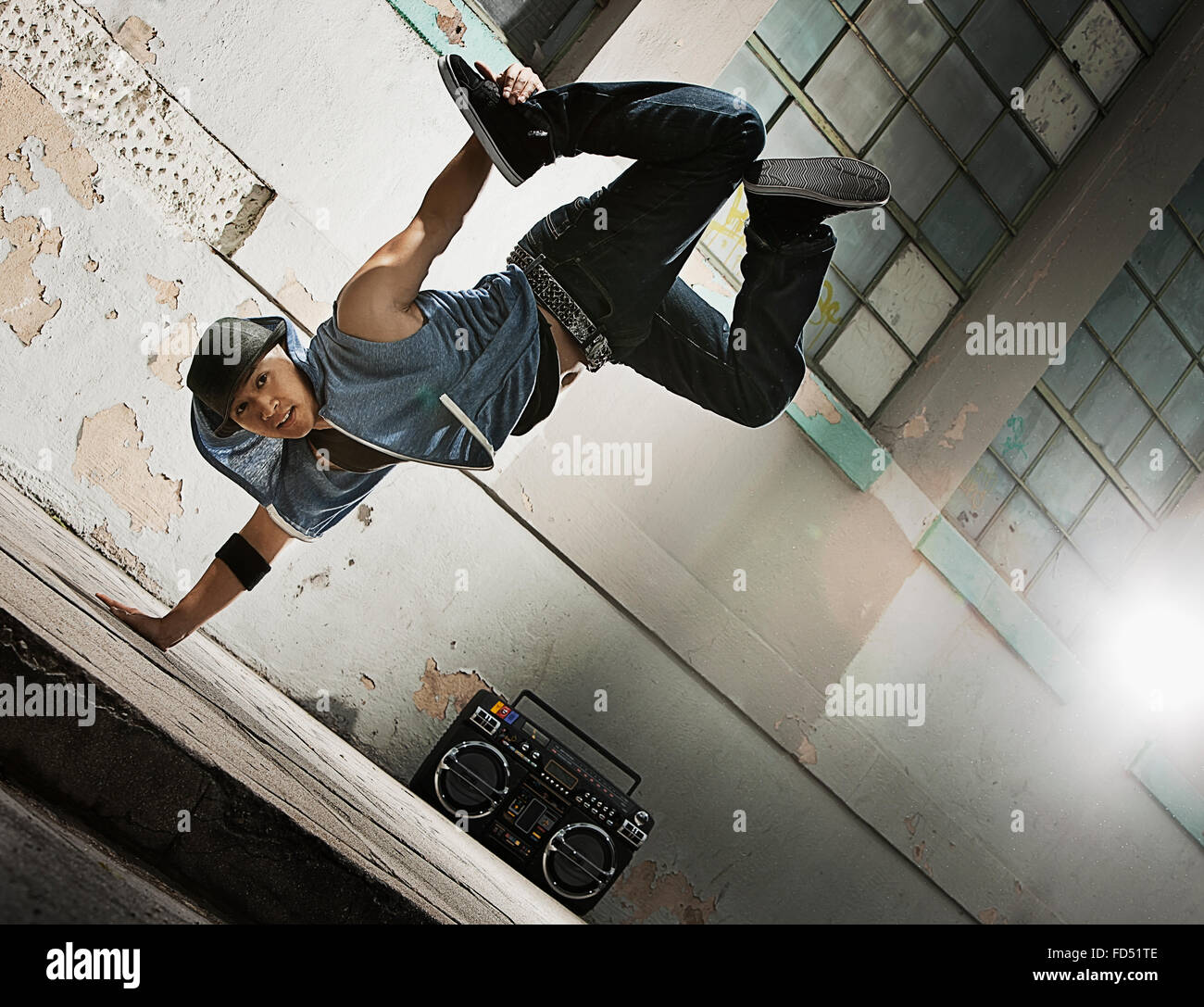 Un giovane uomo di breakdance sulla strada di una città, facendo un una sola mano handstand. Foto Stock
