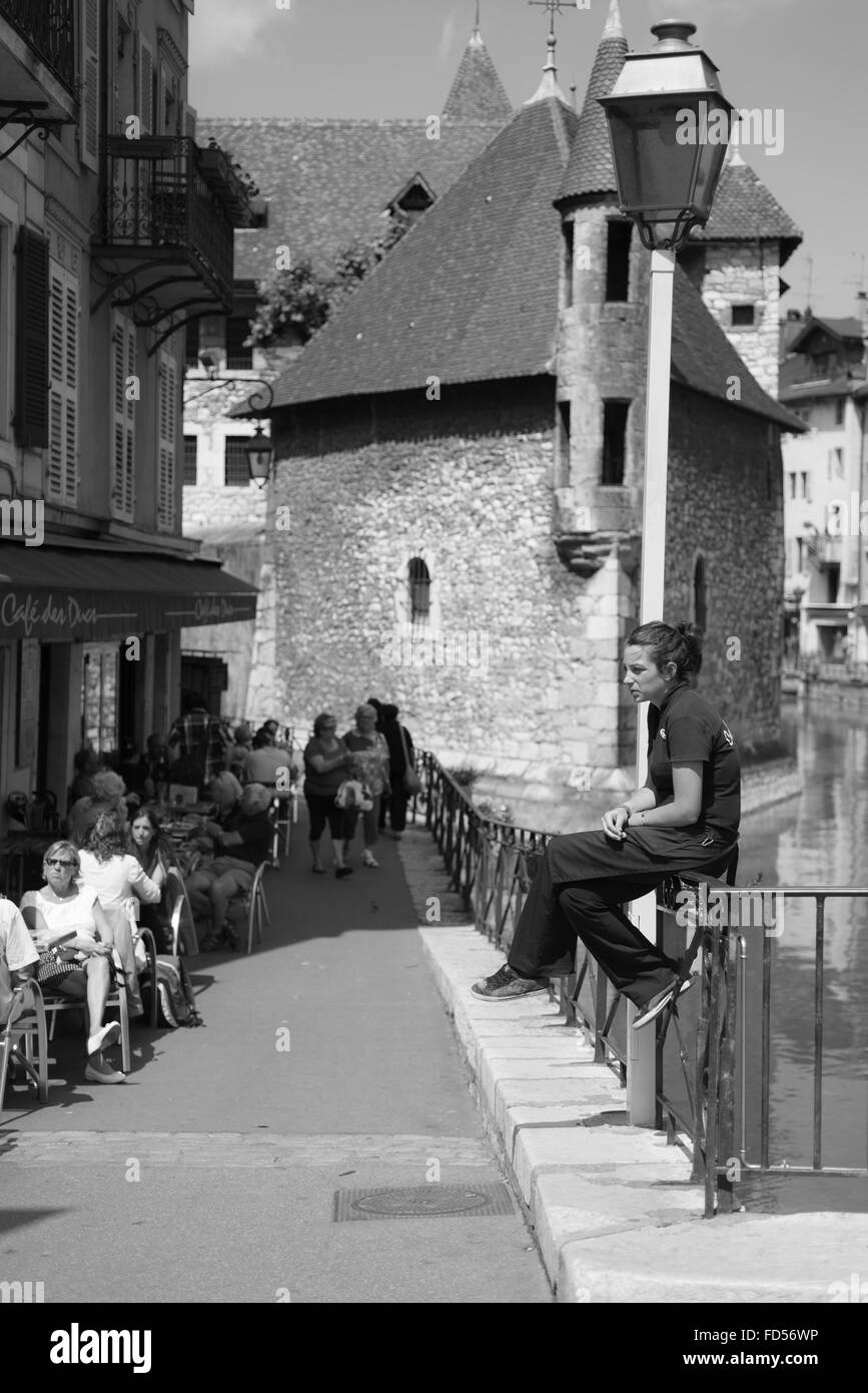 Pausa sigaretta di una giovane cameriera di fronte al Palais de l'Isle presso il fiume Thiou in Annecy in Francia su una mattina d'estate Foto Stock