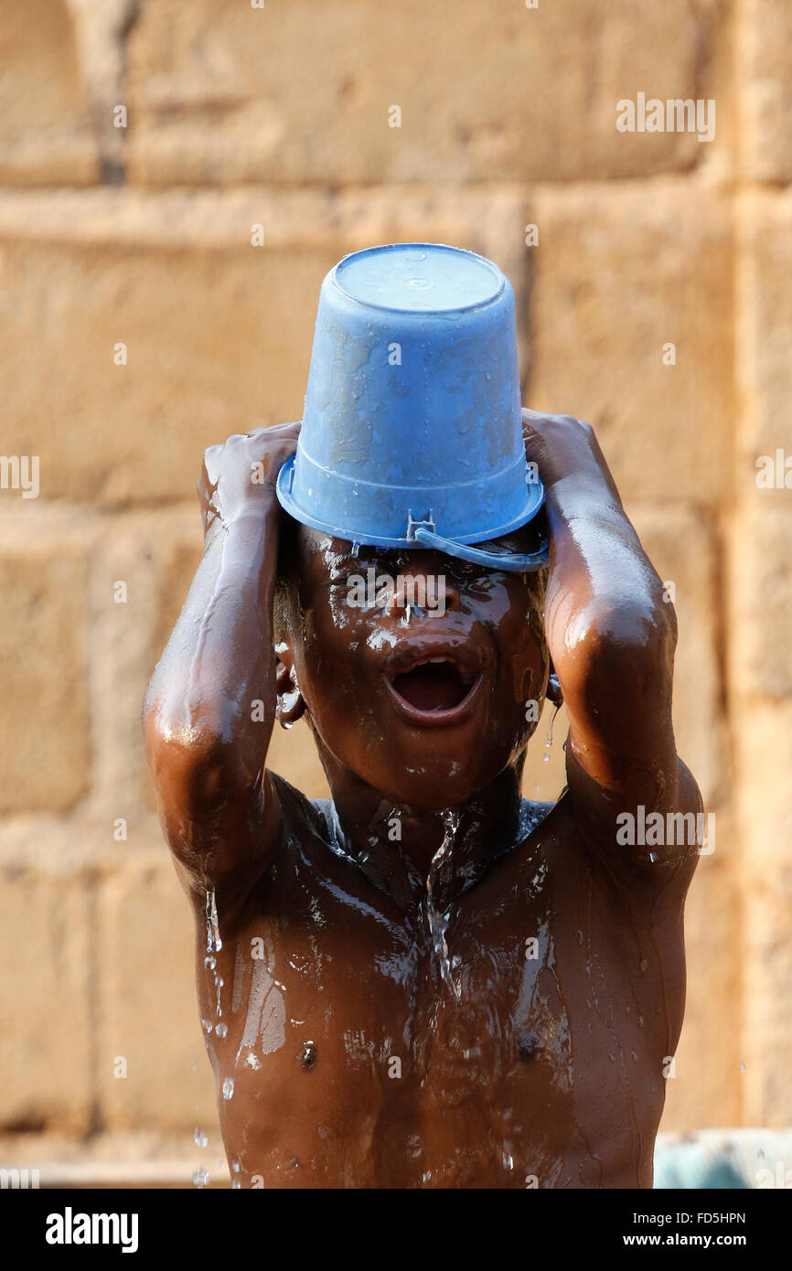 Bambino africano avente una doccia a casa. Foto Stock