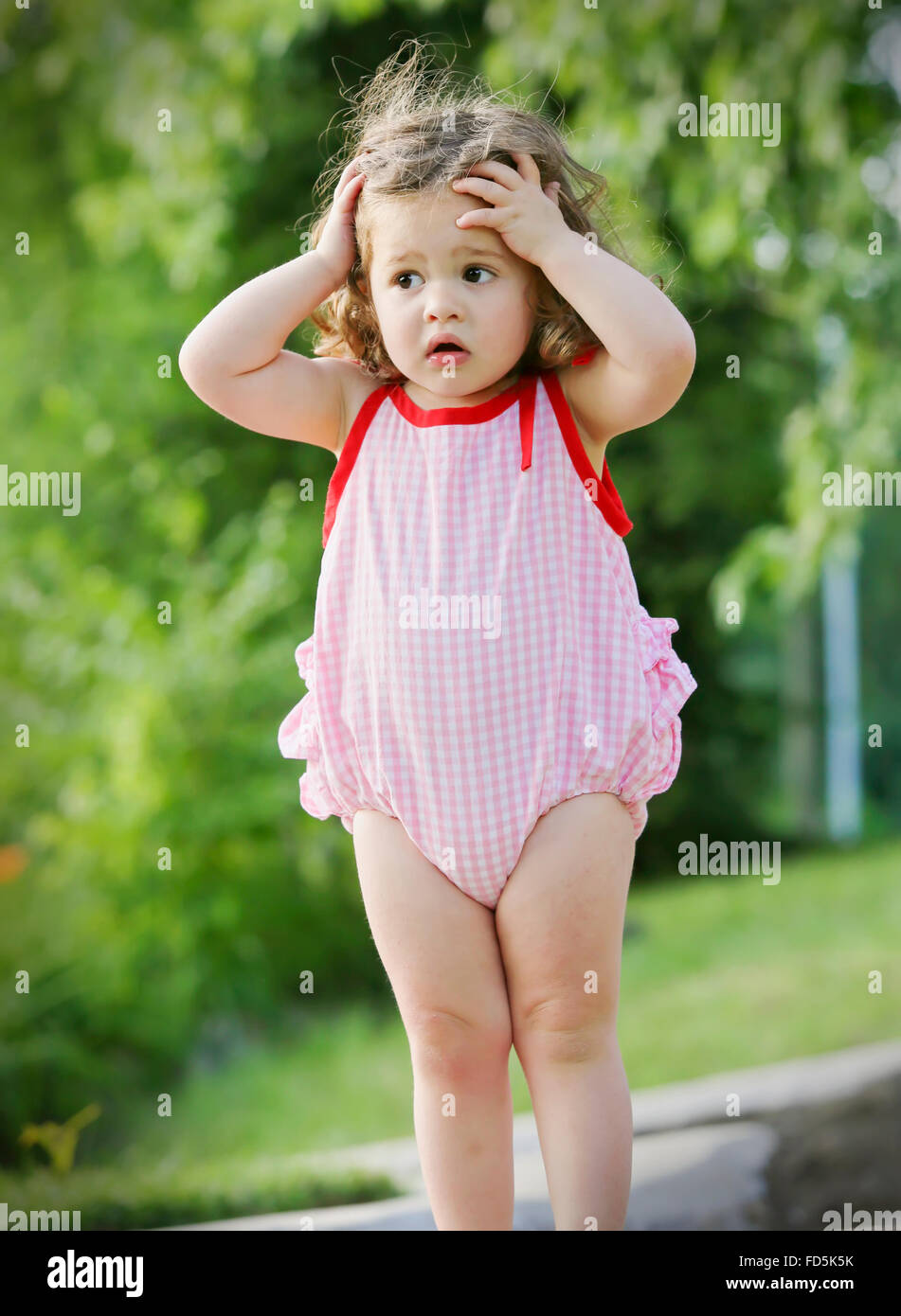 Bimbi preziosi in piedi al di fuori con le mani sul suo capo e un'espressione preoccupata sul suo viso. Foto Stock