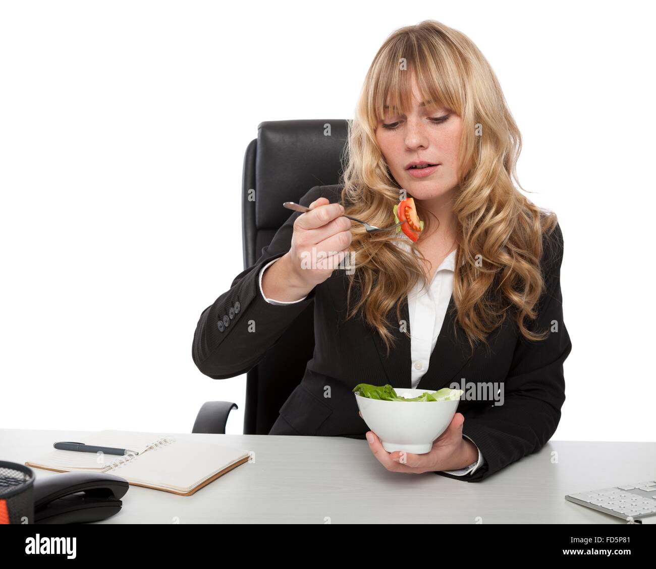 Sano bella bionda e giovane imprenditrice mangiare una tazza di insalata fresca alla sua scrivania Foto Stock