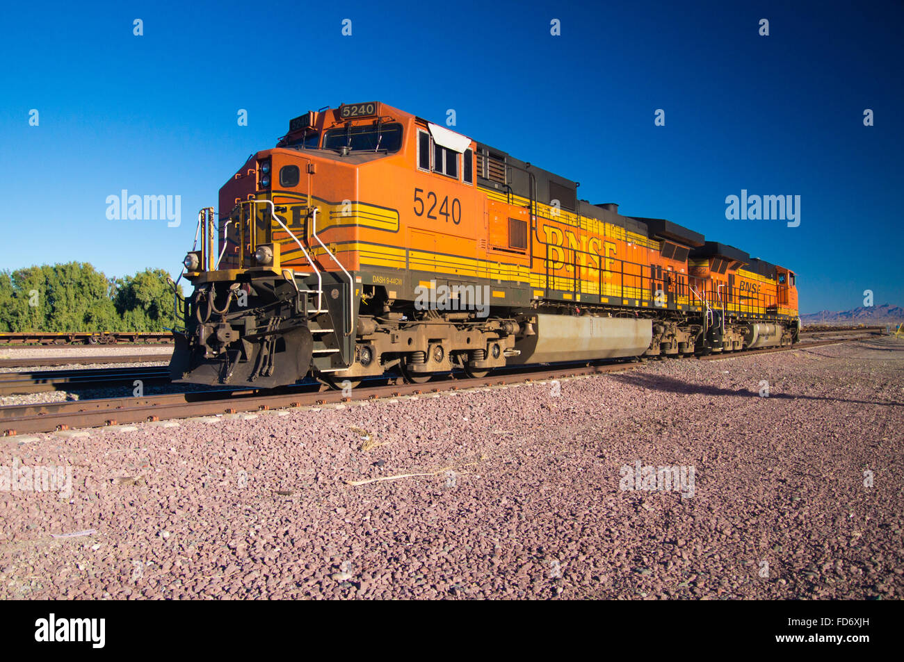 Carattere distintivo arancione e giallo Burlington Northern Santa Fe locomotiva treno merci n. 5240 sulle piste presso la città di ago Foto Stock