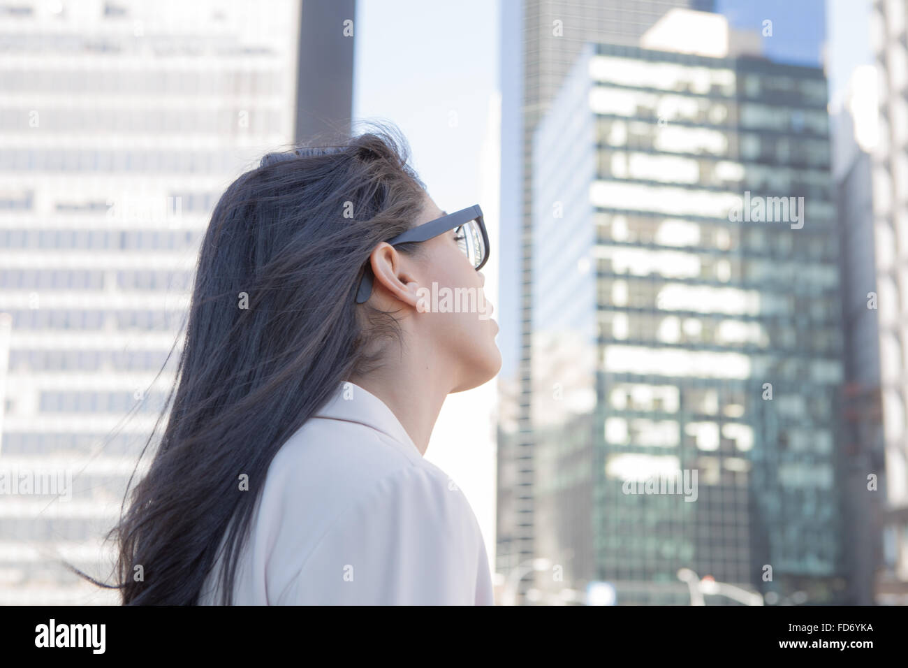 Giovani latino donna professionale con gli occhiali osservando gli edifici della città. Fotografato a New York nel novembre 2015 Foto Stock
